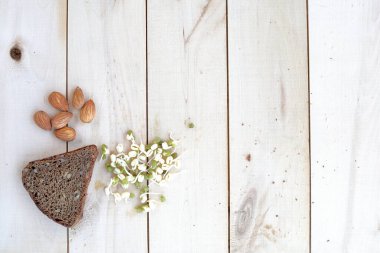 Sağlıklı yiyecek, ekmek, fındık ve filizlenmiş fasulye, ahşap bir ekolojik arka plana yayılmış.