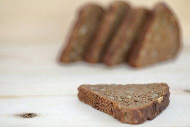 Ahşap zemin üzerinde dilimlenmiş çavdar ekmeği sağlıklı bir şekilde yiyor.