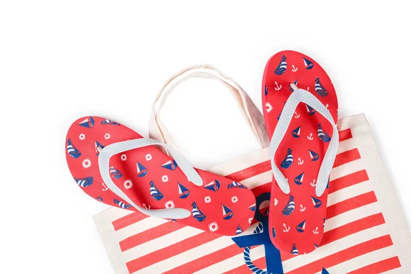 Set van rood flip flops en kleurrijke gestreepte print strandtas geïsoleerd op een witte achtergrond. Bovenaanzicht — Stockfoto