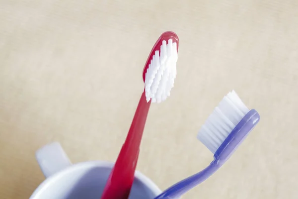 Närbild av röda och blå plast tandborstar i glas koncept tandvård — Stockfoto