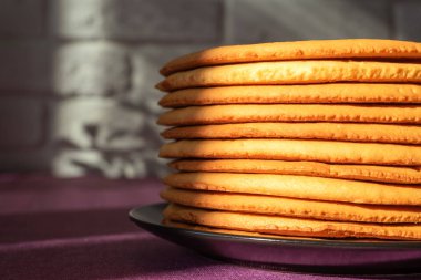 Evde ballı kek pişirmek. Bir tabağa istiflenmiş yuvarlak kek katmanları.