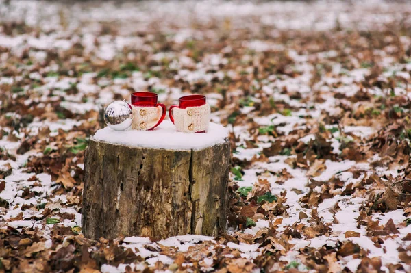Чашки и рождественский бал на пне — стоковое фото