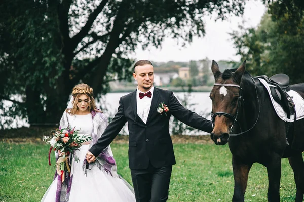 Jovem casal com um cavalo preto — Fotografia de Stock