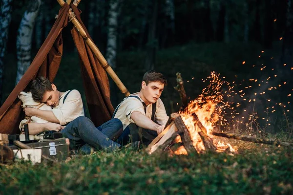 Irmãos gêmeos sentados em torno de uma fogueira — Fotografia de Stock