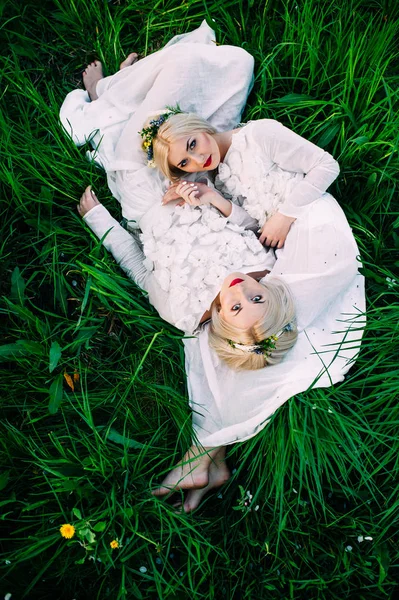 Сёстры близнецы лежат на траве — стоковое фото