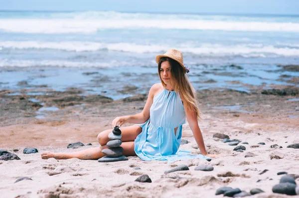 Montón de piedras de guijarro en la playa con una hermosa mujer behin —  Fotos de Stock
