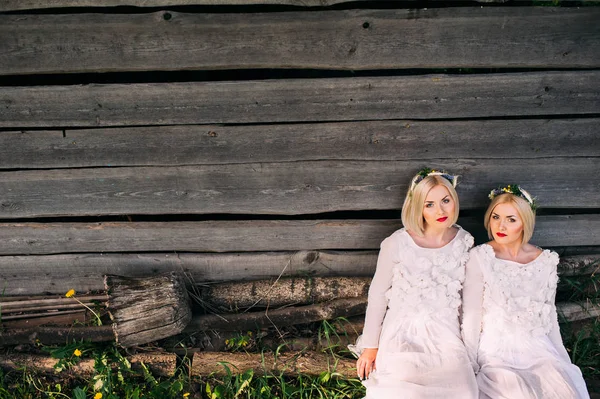 Sestry-dvojčata sedící u zdi — Stock fotografie