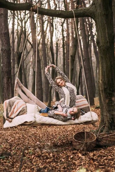 Hermanas gemelas en swing en el bosque — Foto de Stock