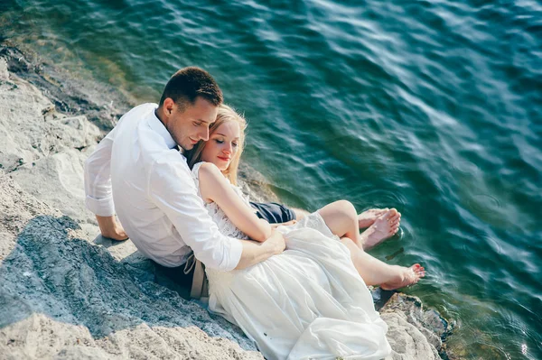 Jeune couple assis sur la plage — Photo