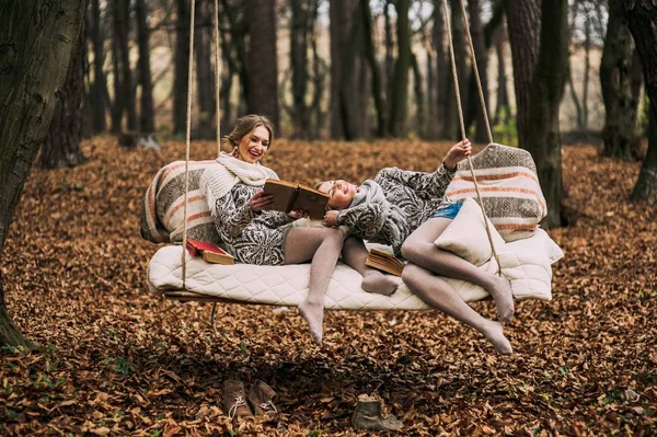 Twin sister on swing in forest — стоковое фото