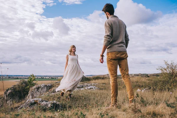 young beautiful couple in the field near the mountains