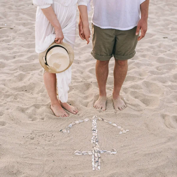 在沙滩上的年轻夫妇奠定了贝壳的锚 — 图库照片
