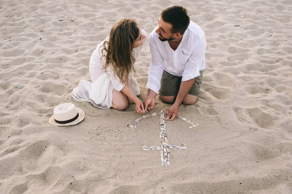 在沙滩上的年轻夫妇奠定了贝壳的锚 — 图库照片