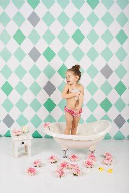 Beyaz kız çiçek yakınındaki su oyuncakları ile oynarken