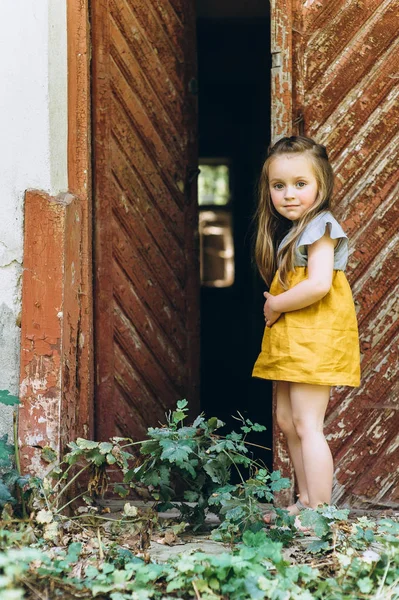 Menina Bonito Vestido Amarelo Perto Uma Porta Madeira — Fotografia de Stock