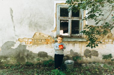 küçük sarışın çocuk kırmızı kupa ve arka plan üzerine bir kova ile