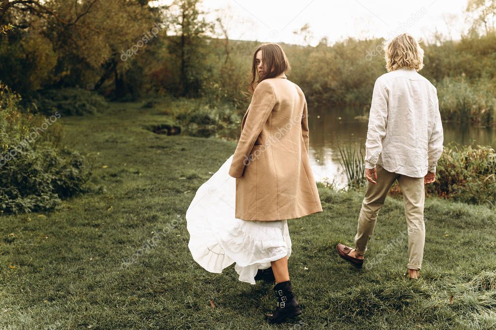 beautiful young couple dressed in boho style walking in the sunny forest