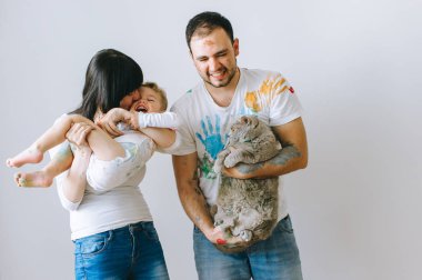 Genç aile evlat ve kedi ile oynadıktan sonra beyaz bir arka plan üzerine boyar