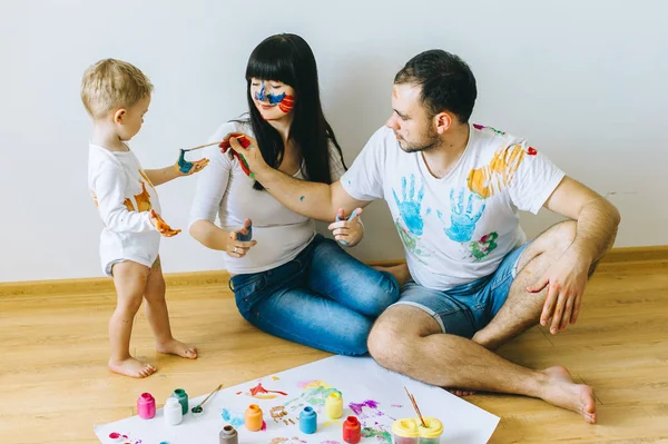 happy family painting a poster and one another with paints