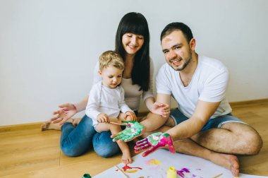 küçük çocuk anne ve bir kedi bir poster ve başka bir boya ile resim