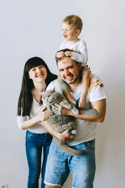 Genç aile evlat ve kedi ile oynadıktan sonra beyaz bir arka plan üzerine boyar
