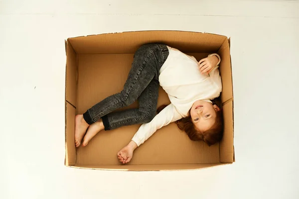 A little girl in a cardboard boxes at new home on a white backgr — Stock Photo, Image
