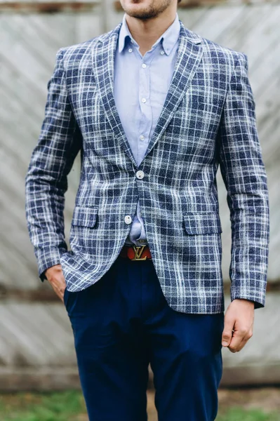 A young handsome groom holding a bouquet of daisies near old hou — Stock Photo, Image