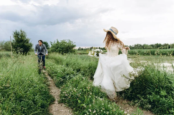 Belle jeune mariée couple et marié marche dans un champ avec un — Photo