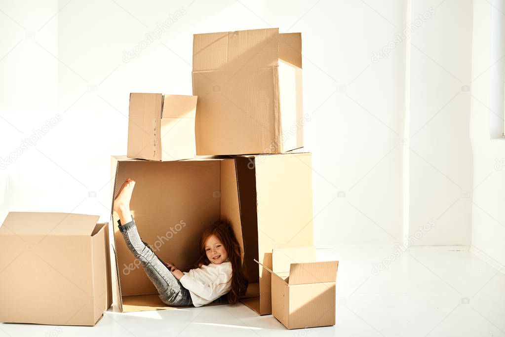 A little girl in a cardboard boxes at new home on a white backgr