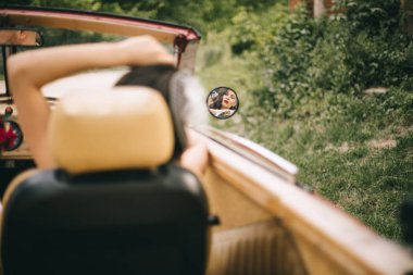 Eski bir arabada şık, güzel bir gelin. Harika. Ayna görünümü