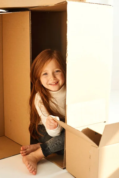 สาวน้อยในกล่องกระดาษแข็งที่บ้านใหม่บน backgr สีขาว — ภาพถ่ายสต็อก