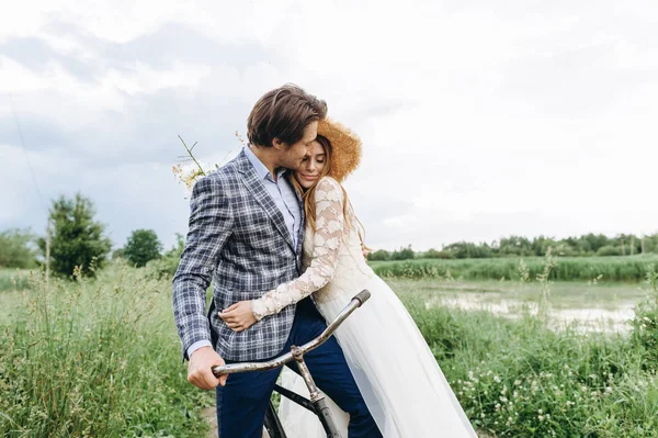 Casal jovem bonita noiva e noivo andando em um campo com um — Fotografia de Stock