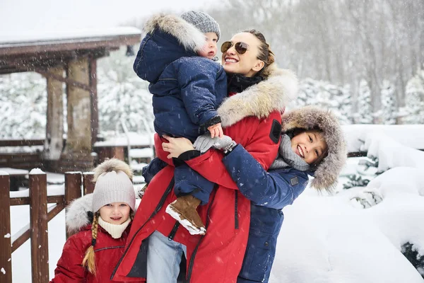 Eine junge Mutter mit ihren drei Kindern hat Spaß und spielt sno — Stockfoto