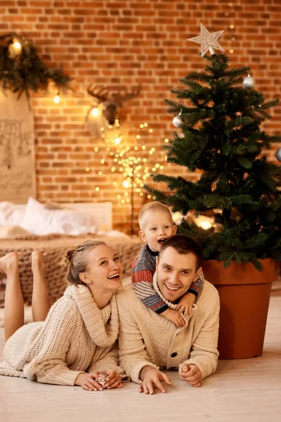 Eine glückliche junge Familie im Schlafzimmer schmückt den Weihnachtsbaum — Stockfoto