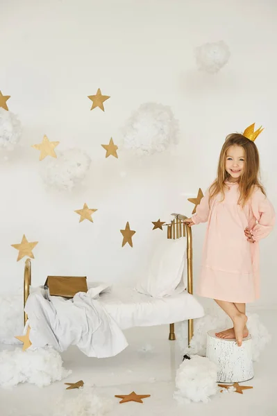 Malá princezna s kouzelnou hůlkou na posteli v mraku na bílém pozadí — Stock fotografie
