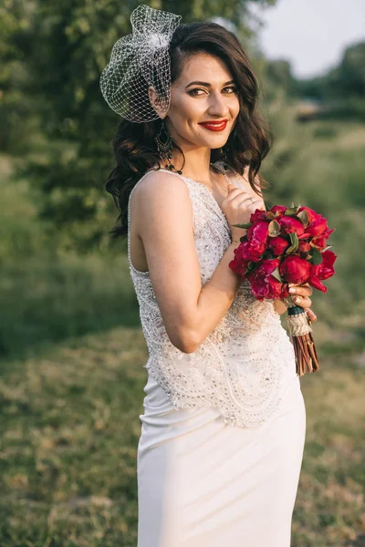 Stylish bride with a bouquet in a field near the lake. Retro sty — Stock Photo, Image