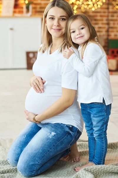 Um retrato de uma pequena filha com sua mãe grávida no — Fotografia de Stock