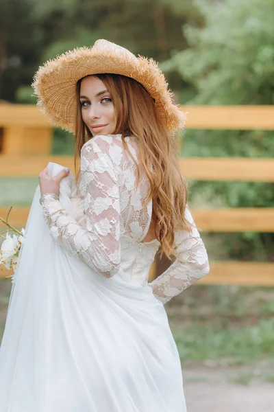 A beautiful young bride with a bouquet of daisies in a field — Stock Photo, Image