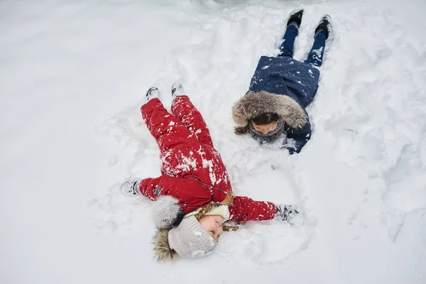 En söt barn leker i snö utomhus nära julgranen — Stockfoto