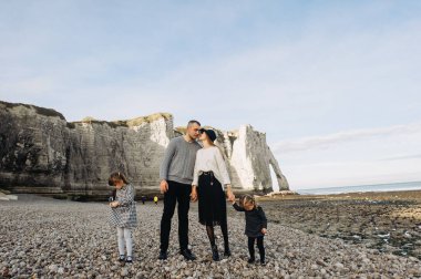 Okyanusun kumlu sahillerinde güzel, genç bir aile dinleniyor ve eğleniyor.