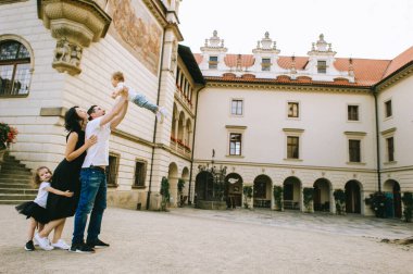 Yakışıklı genç baba ve güzel anne güneşli yaz doğasında sevimli küçük çocuklarıyla oynuyorlar.