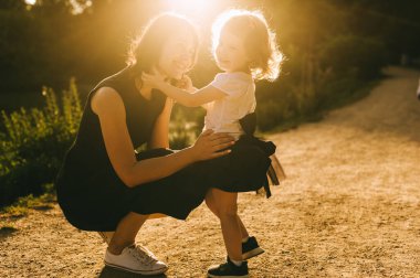 Yakışıklı genç baba ve güzel anne güneşli yaz doğasında sevimli küçük çocuklarıyla oynuyorlar.