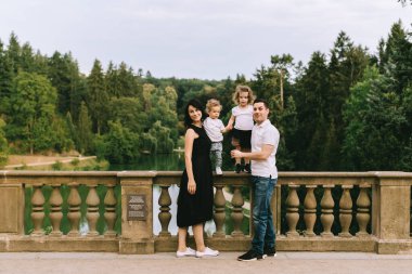 Yakışıklı genç baba ve güzel anne güneşli yaz doğasında sevimli küçük çocuklarıyla oynuyorlar.