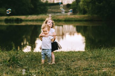 Yakışıklı genç baba ve güzel anne güneşli yaz doğasında sevimli küçük çocuklarıyla oynuyorlar.