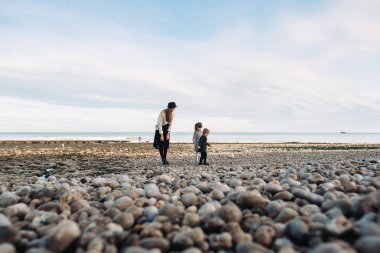 Okyanusun kumlu sahillerinde güzel, genç bir aile dinleniyor ve eğleniyor.