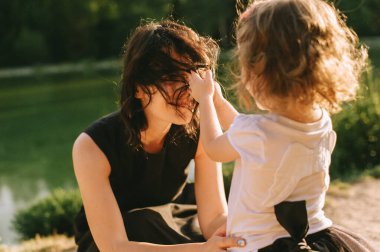 Yakışıklı genç baba ve güzel anne güneşli yaz doğasında sevimli küçük çocuklarıyla oynuyorlar.