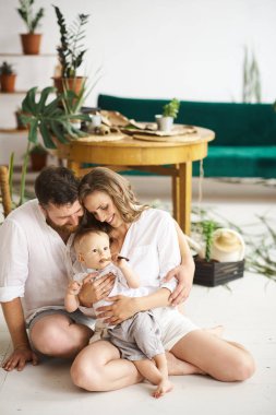 Evde çalışan mutlu bir aile. Çocuklarıyla birlikte bitkileri naklediyorlar.