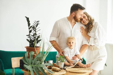 Evde çalışan mutlu bir aile. Çocuklarıyla birlikte bitkileri naklediyorlar.