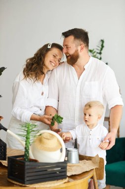 Evde çalışan mutlu bir aile. Çocuklarıyla birlikte bitkileri naklediyorlar.