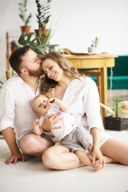 Evde çalışan mutlu bir aile. Çocuklarıyla birlikte bitkileri naklediyorlar.